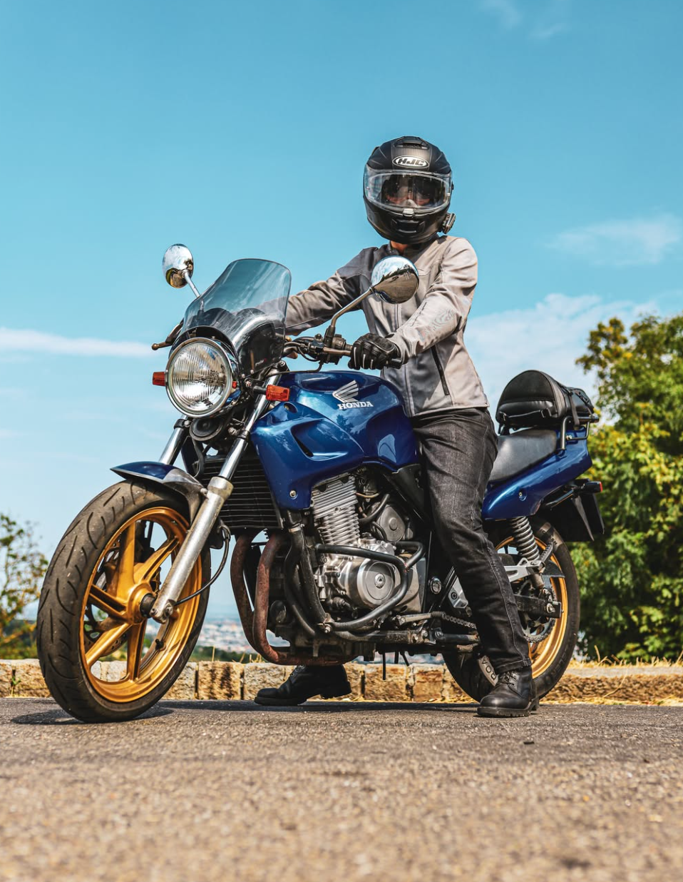 Fahrerin auf einer blauen Honda vor sommerlicher Landschaft